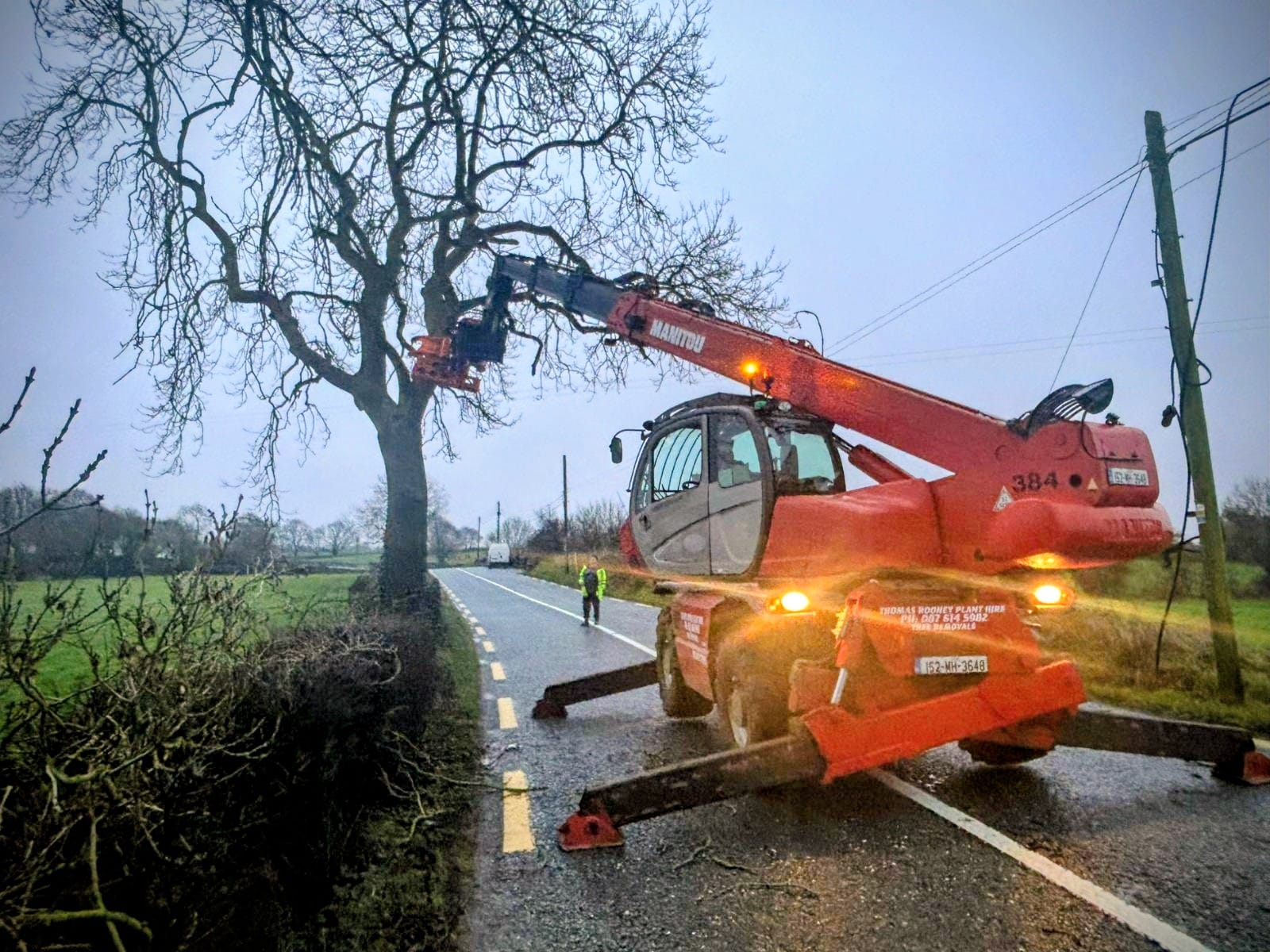 Emergency tree work at dusk on a rural Meath road with hi-vis operator